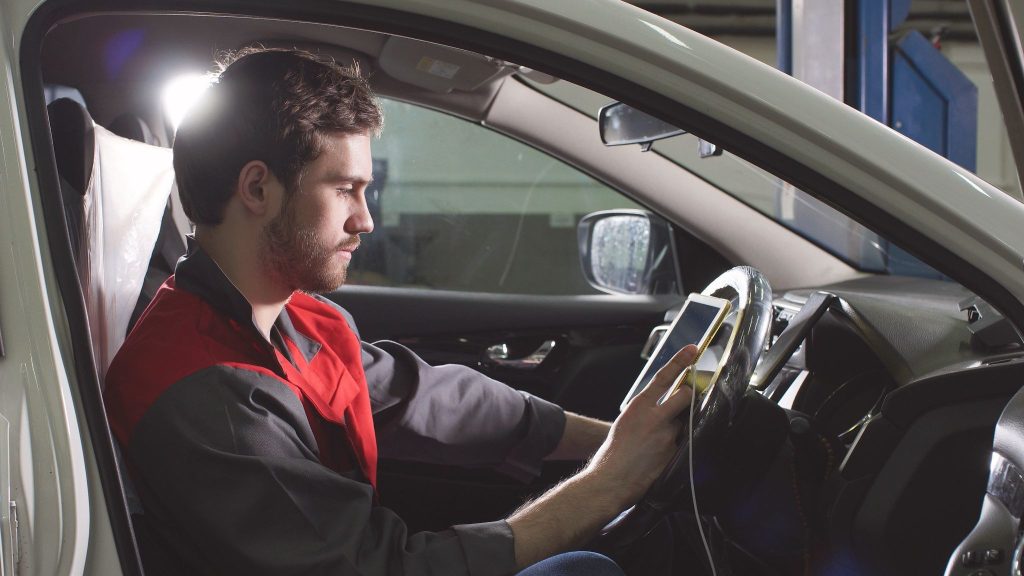 An automotive student using a scan tool to investigate a steering-angle sensor fault